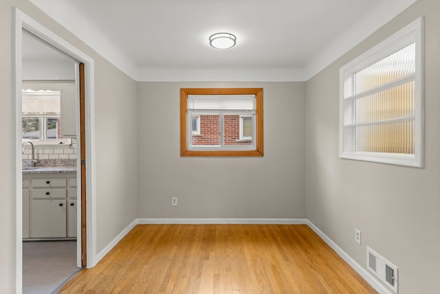 empty room featuring visible vents, light wood-style floors, and baseboards