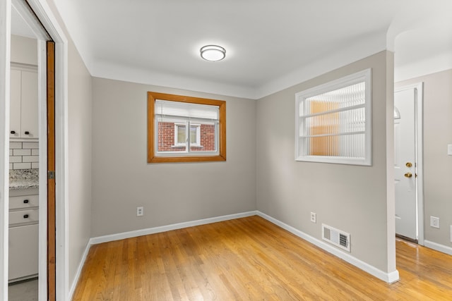 unfurnished bedroom with visible vents, multiple windows, and light wood-style flooring