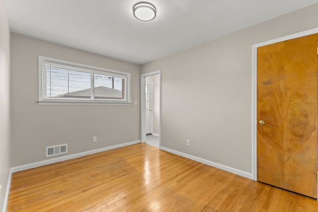 empty room featuring visible vents, light wood-style floors, and baseboards