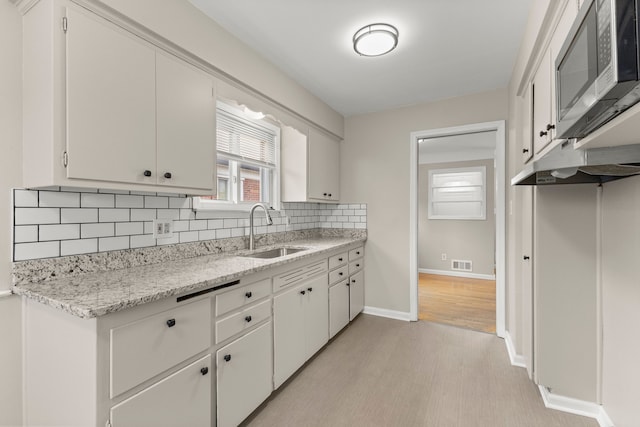 kitchen featuring decorative backsplash, visible vents, a sink, baseboards, and stainless steel microwave