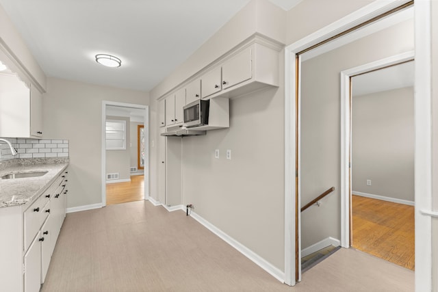 kitchen featuring backsplash, visible vents, a sink, white cabinets, and stainless steel microwave