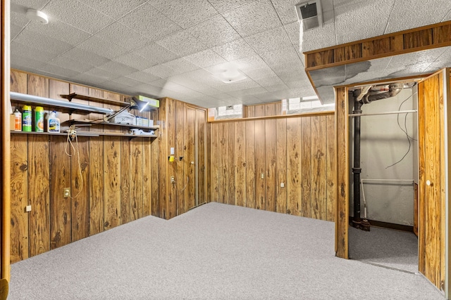 below grade area featuring carpet flooring, wooden walls, and visible vents