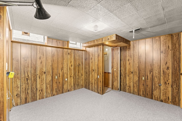 basement featuring wooden walls, carpet flooring, and visible vents