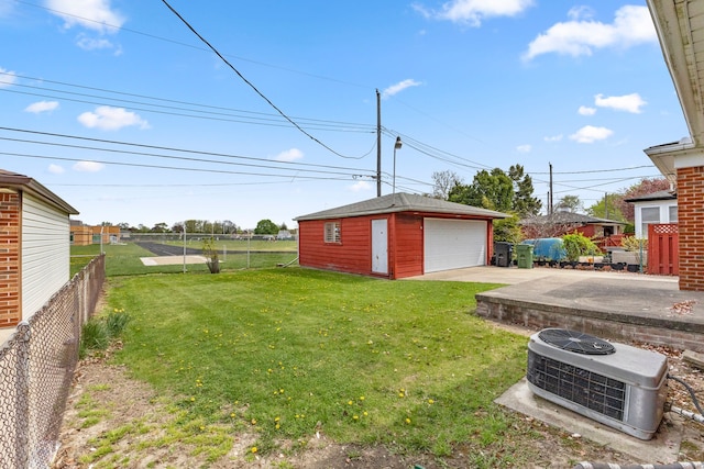 view of yard with fence, central AC unit, an outdoor structure, and a garage