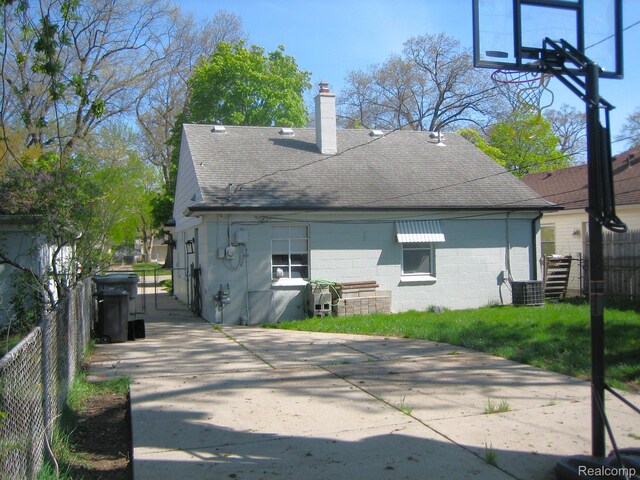 24101 Carlysle St, Dearborn, MI 48124 - back of house featuring roof with shingles, a chimney, and concrete block siding