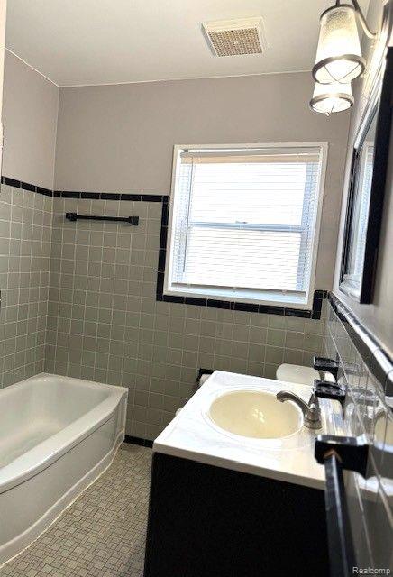 24101 Carlysle St, Dearborn, MI 48124 - bathroom with tile walls, a bathtub, and vanity