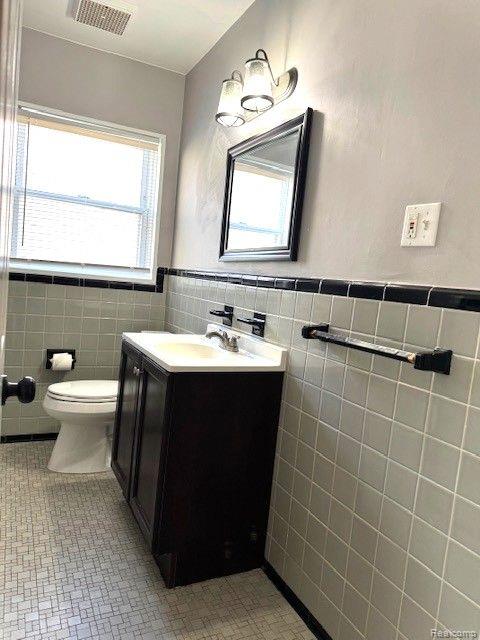 24101 Carlysle St, Dearborn, MI 48124 - bathroom featuring tile walls, vanity, wainscoting, and tile patterned flooring