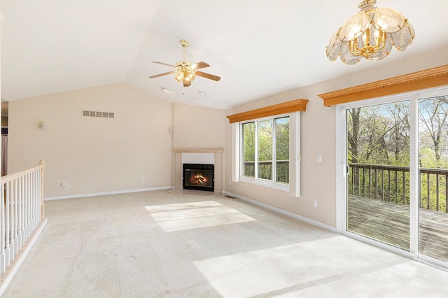 unfurnished living room with light carpet, ceiling fan with notable chandelier, baseboards, lofted ceiling, and visible vents