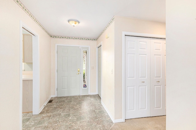 entrance foyer featuring baseboards, stone finish flooring, and visible vents