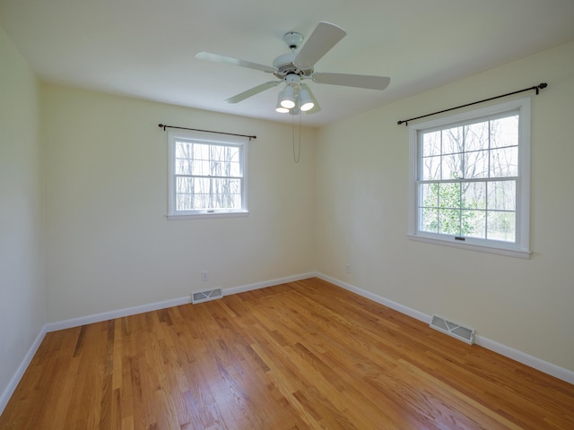 spare room featuring visible vents, light wood finished floors, and a healthy amount of sunlight