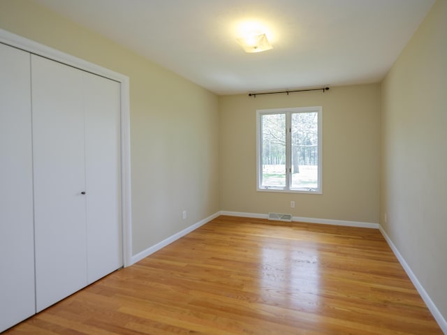 unfurnished bedroom featuring baseboards, visible vents, light wood-style flooring, and a closet