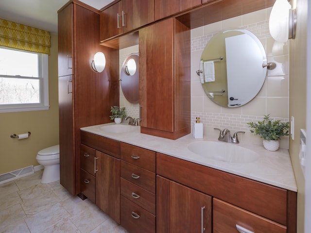 full bath with visible vents, a sink, backsplash, and toilet