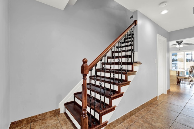 stairway with baseboards and ceiling fan