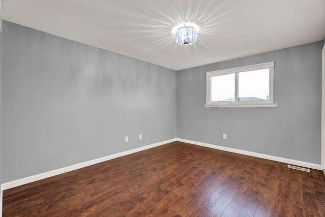 spare room featuring baseboards, visible vents, and wood finished floors