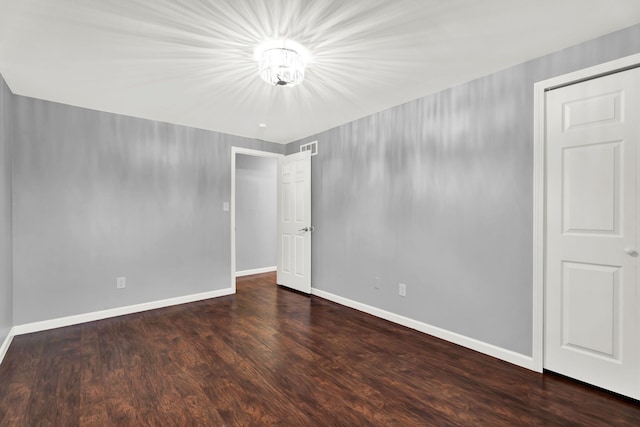 spare room with baseboards, wood finished floors, and visible vents
