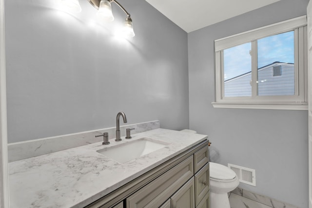 half bath featuring vanity, toilet, marble finish floor, and visible vents