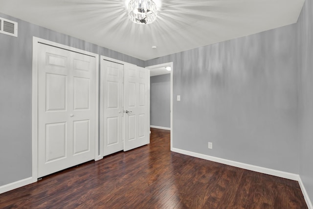 unfurnished bedroom with visible vents, baseboards, dark wood finished floors, and a closet