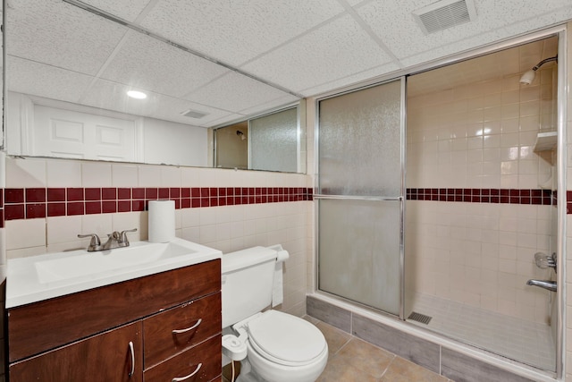 bathroom featuring a paneled ceiling, visible vents, a stall shower, vanity, and toilet