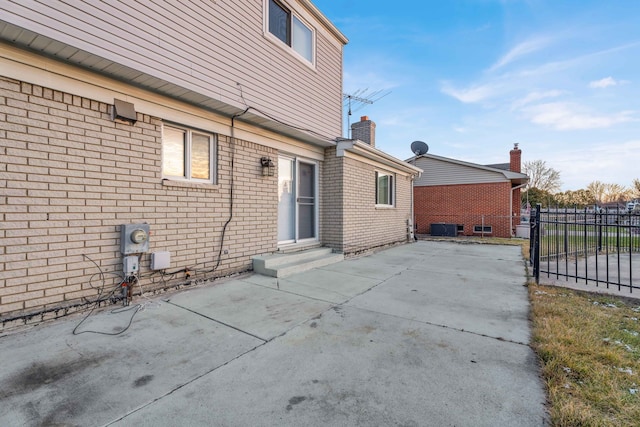 back of property with brick siding, fence, driveway, and a patio