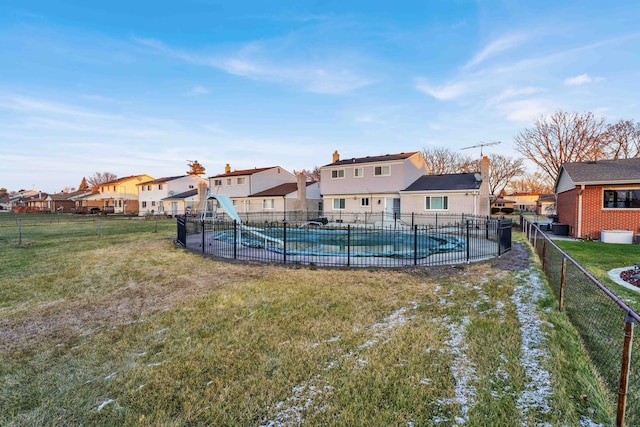 view of swimming pool with a residential view, fence, a fenced in pool, a yard, and a water slide