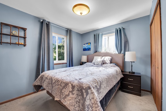 bedroom featuring baseboards, light colored carpet, and multiple windows