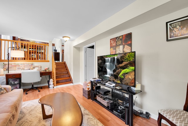 living area with baseboards, wood finished floors, and stairway