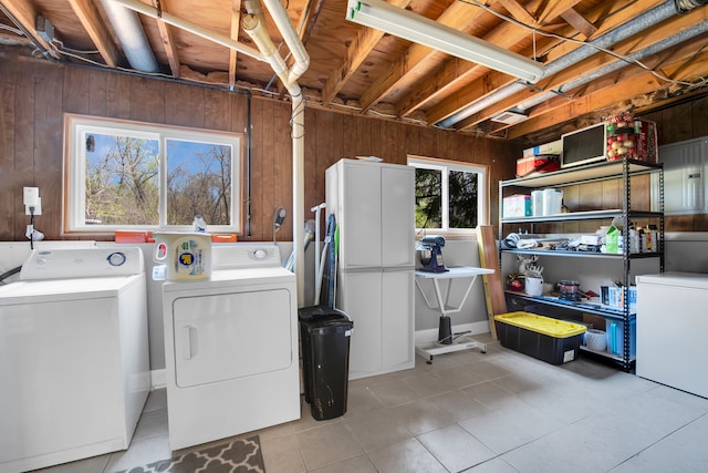 washroom with wooden walls, separate washer and dryer, and laundry area