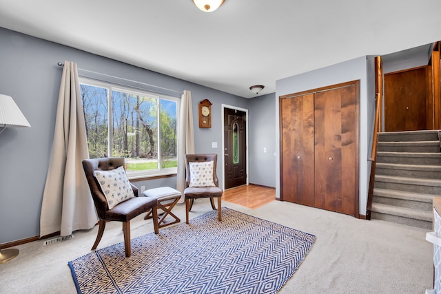 sitting room with stairway, light carpet, and visible vents