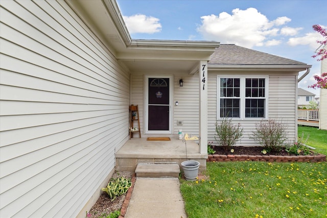 doorway to property with a yard and roof with shingles