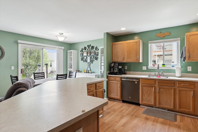 kitchen featuring stainless steel dishwasher, a sink, and light countertops