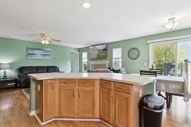 kitchen featuring light countertops, a ceiling fan, open floor plan, and light wood finished floors