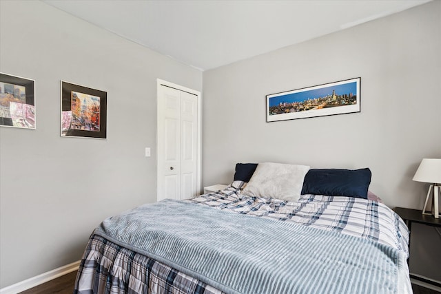 bedroom with baseboards, wood finished floors, and a closet