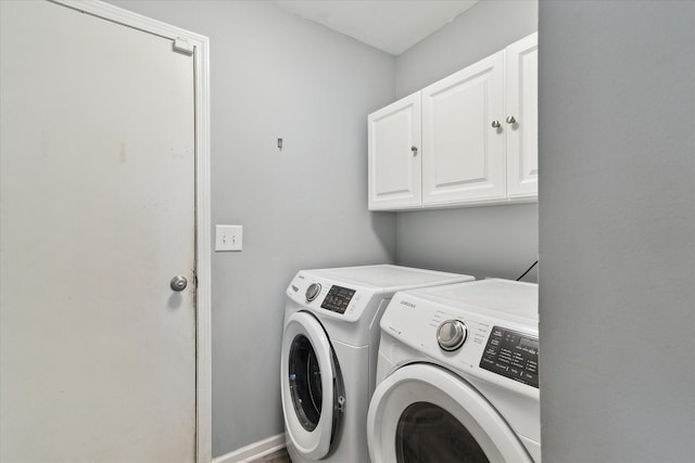 clothes washing area with separate washer and dryer and cabinet space