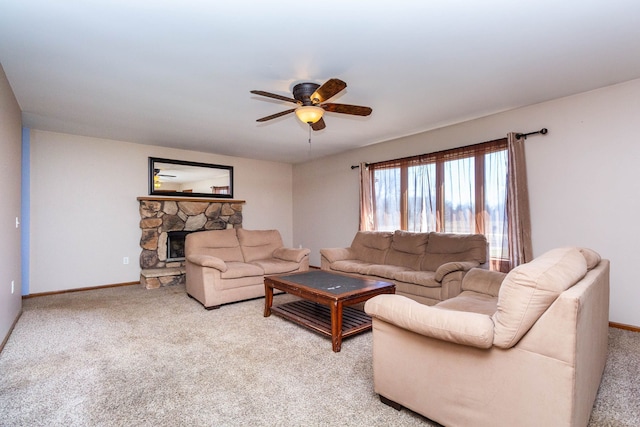 carpeted living area with baseboards, a ceiling fan, and a stone fireplace