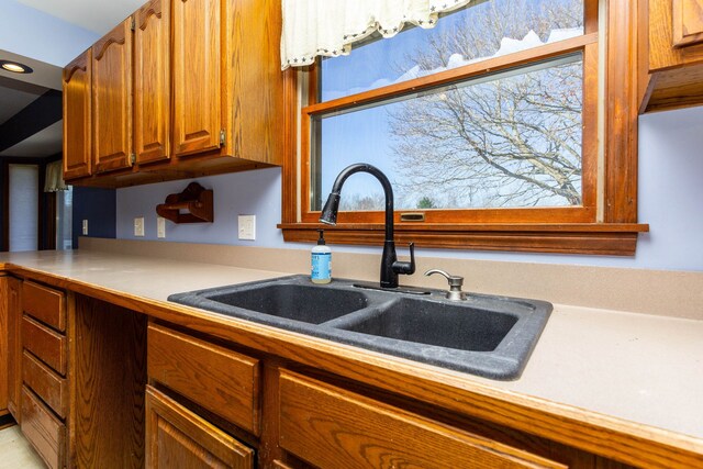 kitchen with a sink, light countertops, and brown cabinetry