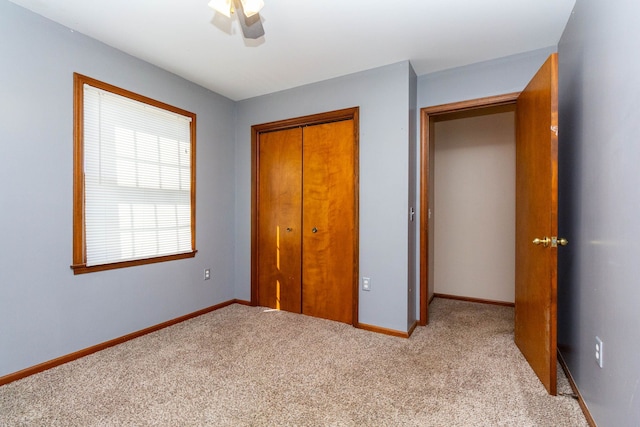 unfurnished bedroom with carpet floors, baseboards, ceiling fan, and a closet