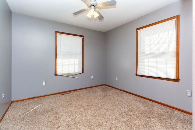 carpeted spare room with a ceiling fan, baseboards, and visible vents