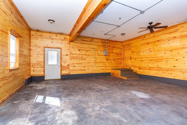 empty room with concrete floors, ceiling fan, and wooden walls