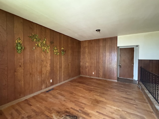 interior space featuring baseboards, wood finished floors, wooden walls, and visible vents