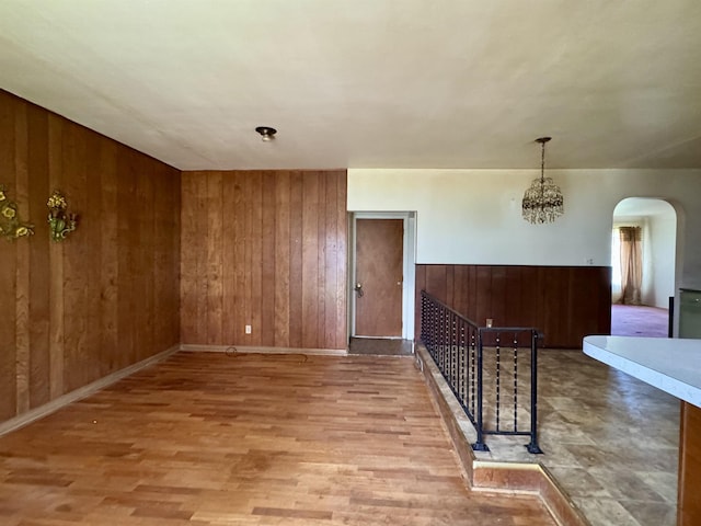 interior space featuring wooden walls, arched walkways, baseboards, and wood finished floors