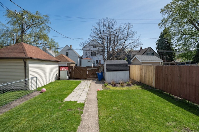 view of yard with a fenced backyard, a shed, an outbuilding, and a gate
