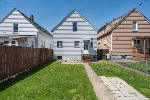 rear view of house featuring entry steps, a yard, a fenced backyard, and central AC