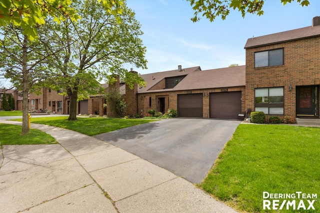 view of front of property featuring brick siding, driveway, a front yard, and a garage
