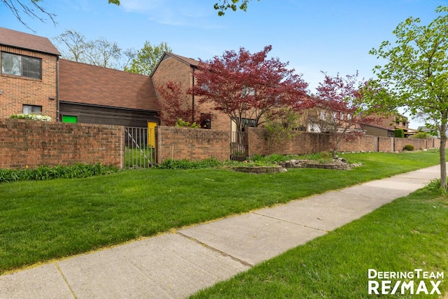 view of front facade featuring brick siding, fence private yard, and a front lawn