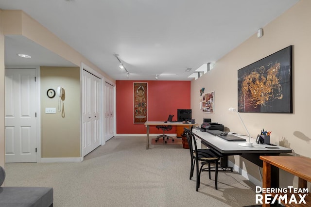 carpeted office space with track lighting and baseboards