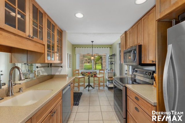 kitchen with a sink, light tile patterned floors, brown cabinets, and stainless steel appliances