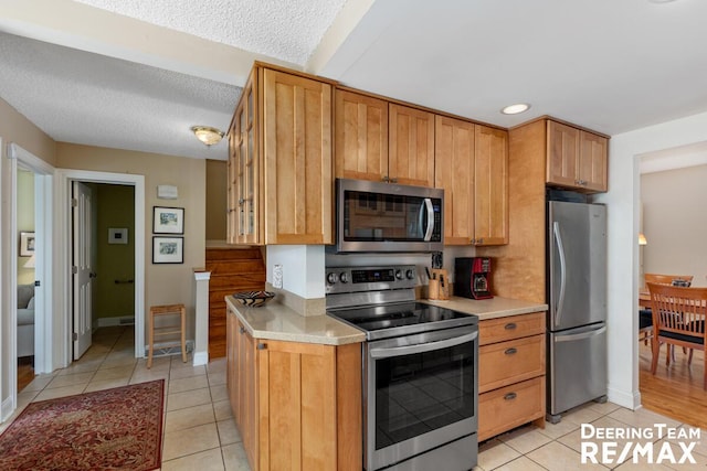 kitchen with appliances with stainless steel finishes, light countertops, baseboards, recessed lighting, and light tile patterned flooring