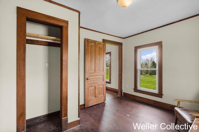 interior space featuring crown molding, baseboards, and dark wood-style floors