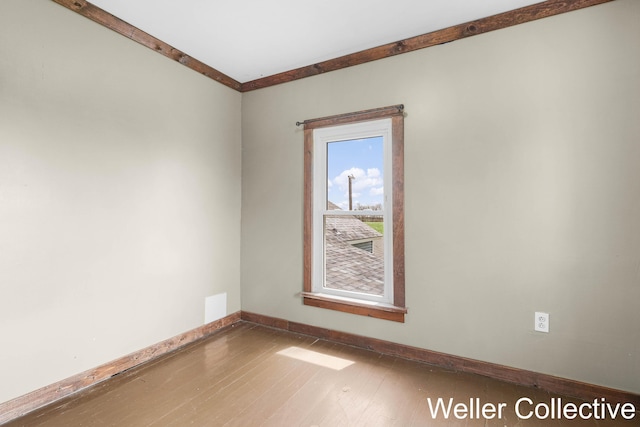 spare room with baseboards and wood finished floors