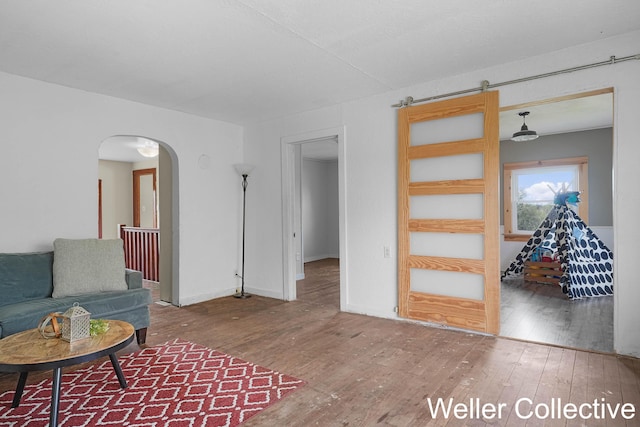 living area featuring arched walkways, baseboards, and hardwood / wood-style flooring